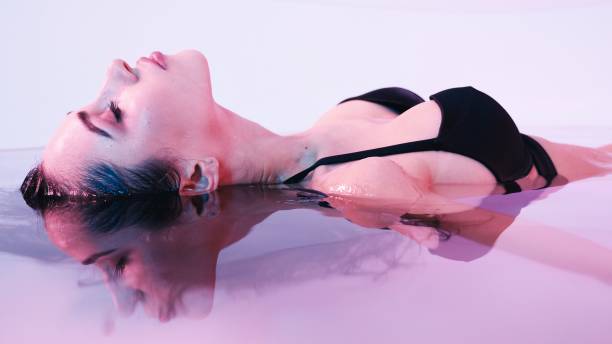 mujer joven flotando en el jacuzzi o la piscina, ella es muy relajada. concepto wellness - heat loss fotografías e imágenes de stock