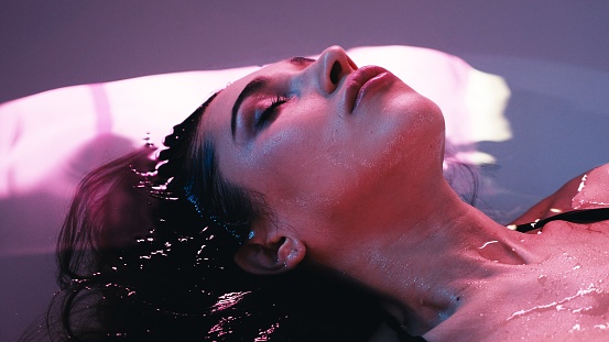 Young woman floating in Spa bath or swimming pool, she is very relaxed. Welness concept.