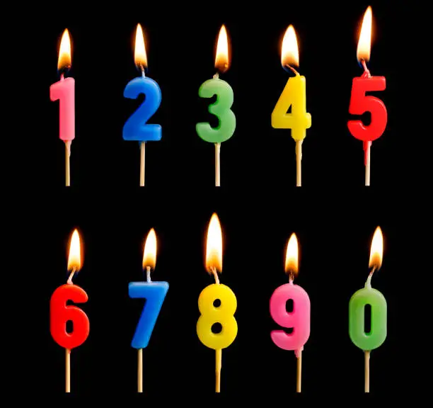 Burning candles in the form of figures (numbers, dates) for cake isolated on black background. The concept of celebrating a birthday, anniversary, important date, holiday, table setting