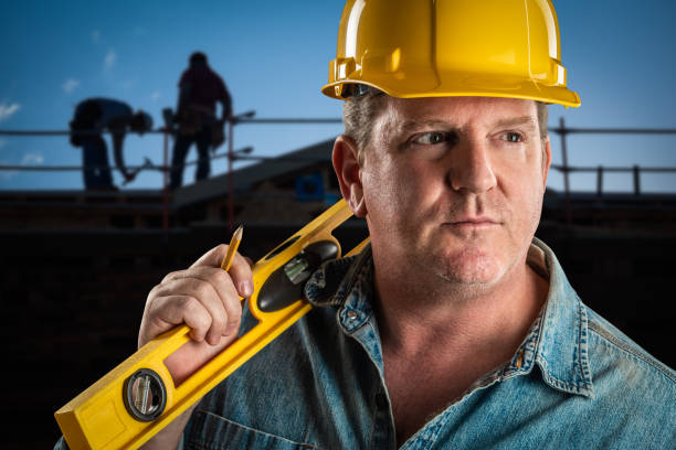 istock Serious Contractor in Hard Hat Holding Level and Pencil At Construction Site. 952036920