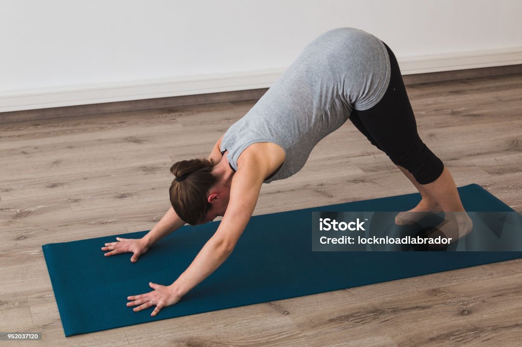 Pregnant woman doing prenatal yoga in downward facing dog posture Pregnant woman doing prenatal yoga in a studio in downward facing dog posture Active Lifestyle Stock Photo