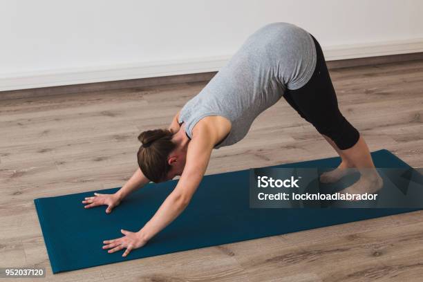Pregnant Woman Doing Prenatal Yoga In Downward Facing Dog Posture Stock Photo - Download Image Now