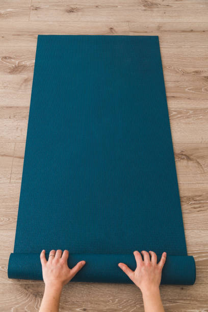 istock Woman rolling out her yoga mat in a studio 952044080