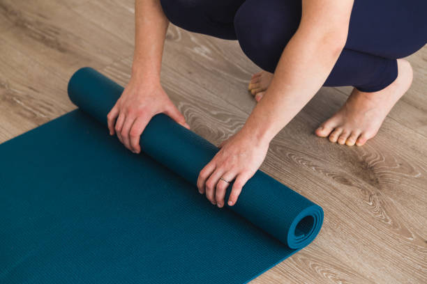 istock Woman unrolling yoga mat in a yoga studio 952045064