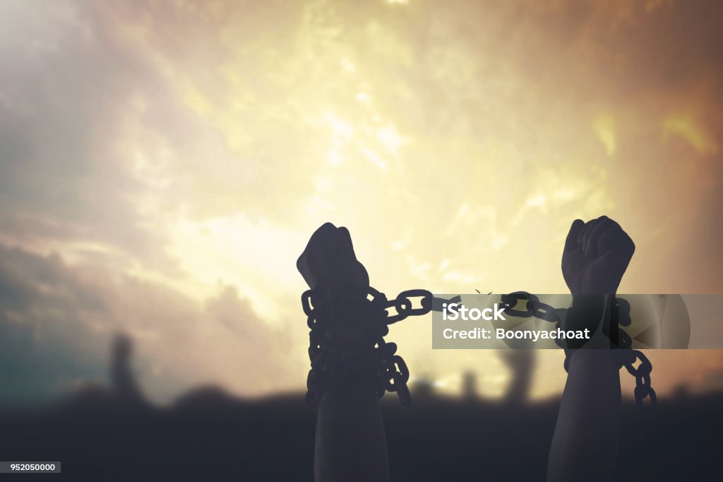 Labor day concept Silhouette human hands raising and broken chains at sunset background Slavery Stock Photo