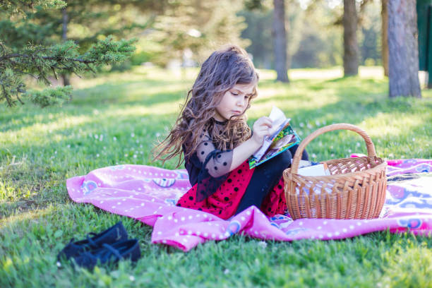 istock Little girl on picnic reading book 952057102