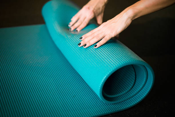 istock Young girl enrolling blue yoga mat after practicing workout and gym. 952057994