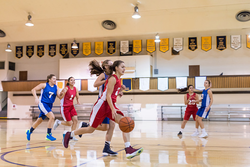 Portrait of a junior basketball player holding a ball on court and smiling at the camera.Copy space. Portrait of young basketball kid standing on basketball court with a ball in his hands and smiling.