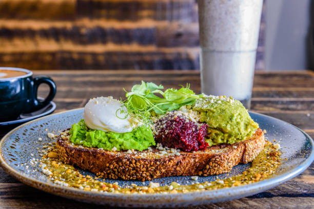 Smashed Avocado A plate of smashed avocado on toast with a poached egg on top brunch photos stock pictures, royalty-free photos & images