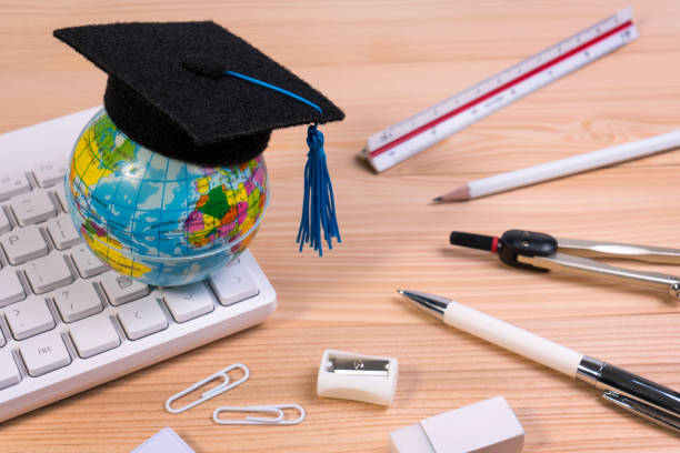 istock School accessories on education table with blank note pad, calculator, pen, keyboard, earth globe model and graduation cap. 952074100