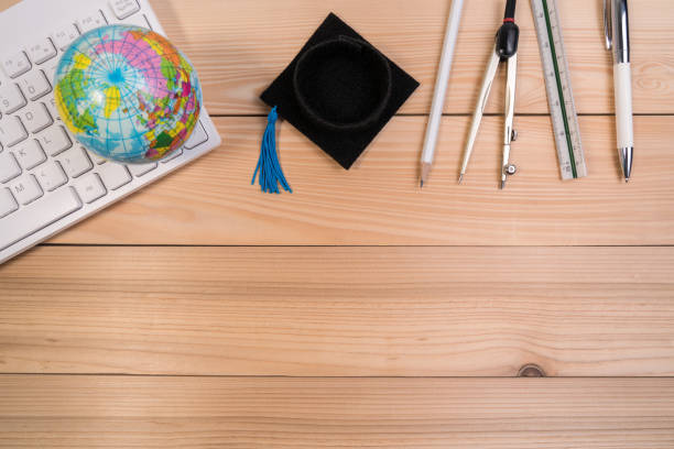 istock School accessories on education table with blank note pad, calculator, pen, keyboard, earth globe model and graduation cap. 952074114