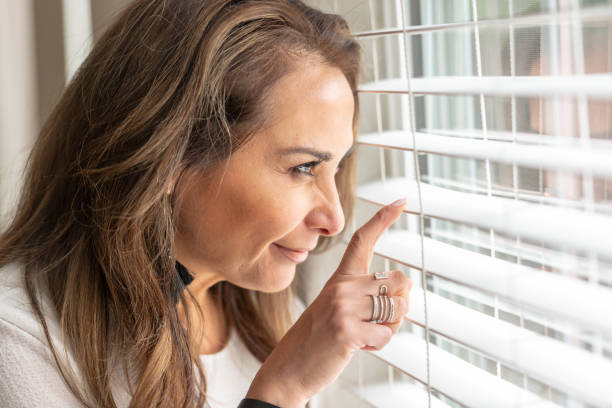istock Mature woman looking through a window 952078564