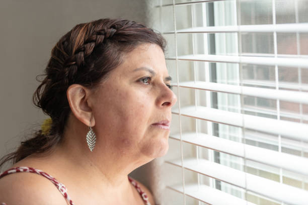 istock Mature woman looking through a window 952078576