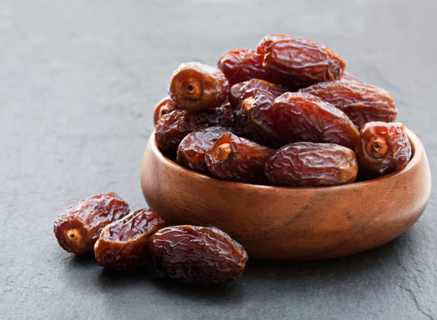 istock Dried  dates in wooden bowl on black stone background 952087178