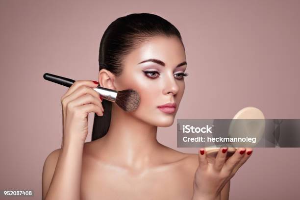 Beautiful Woman Applies Skin Tone With Brush Stock Photo - Download Image Now - Make-Up, Stage Make-Up, Fashion Model