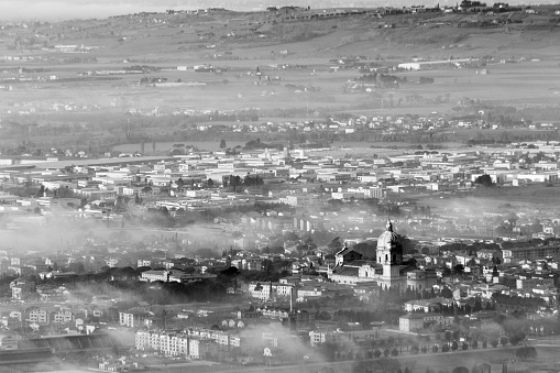 Beautiful aerial view of Santa Maria degli Angeli town (Assisi, Umbria) partially covered by mist and fog