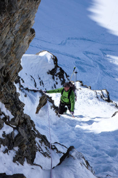 istock mountain guide on a backcountry ski tour rappelling down into and through a narrow snow-filled couloir for an extreme ski descent 952101628