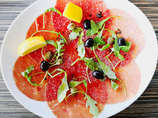 istock Fresh Sliced raw beef meat with leaf lettuce on the table 952101810