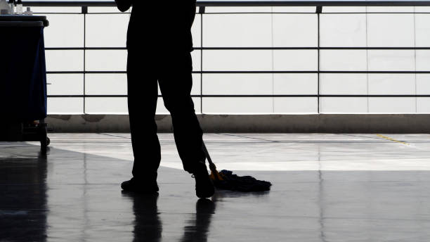 Silhouette image of cleaning service people sweeping floor with mop Silhouette image of cleaning service people sweeping floor with mop and other equipment on trolley. custodian stock pictures, royalty-free photos & images