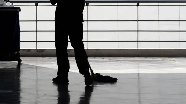 Photo of Silhouette image of cleaning service people sweeping floor with mop