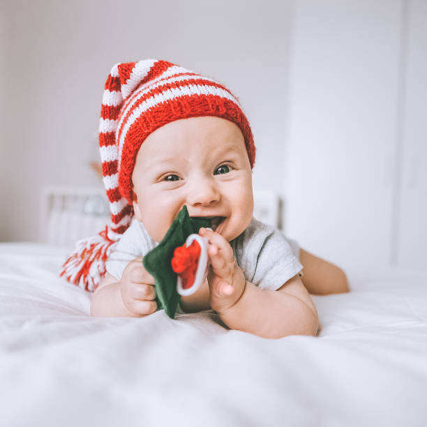 istock infant child in striped hat biting christmas tree toy in bed 952106574