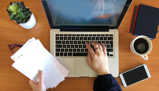 Woman working on laptop top view. Home finance concept.