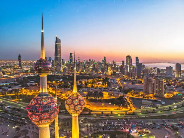 Photo of An aerial shot of the Kuwait Towers during sunset with the view of the skyscrapers at the background.