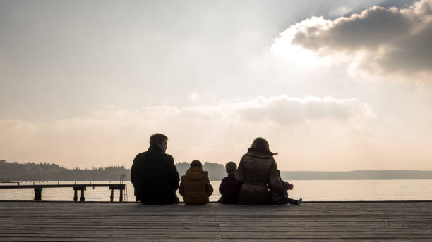 istock Young family sitting on a wooden deck at sunset 952109318