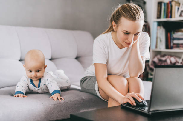istock young mother using laptop while little child lying on couch 952109600