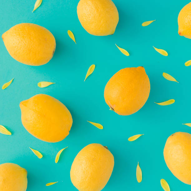istock Creative summer pattern made of lemons and yellow flower petals on bright blue background. Fruit minimal concept. 952114578