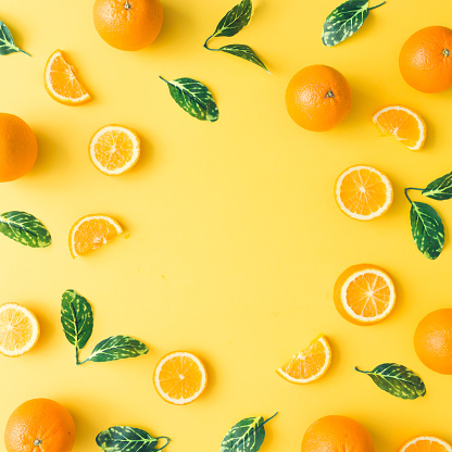 Patrón de verano creativo hecho de naranjas y hojas de color verde sobre fondo amarillo pastel. Concepto mínimo de fruta. La endecha plana. photo