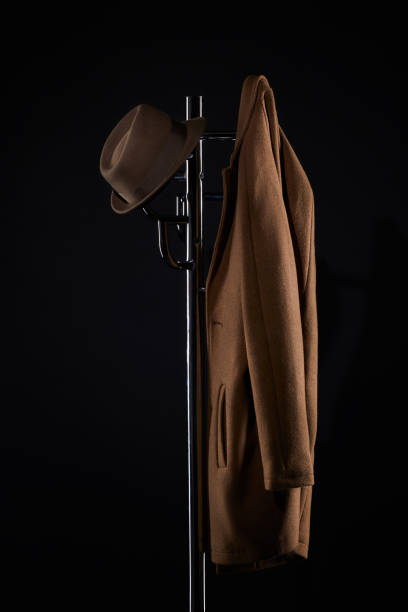 hat and classic jacket hanging on coat rack isolated on black