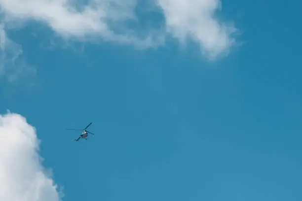 Photo of Flying small helicopter high in a blue cloudy sky.