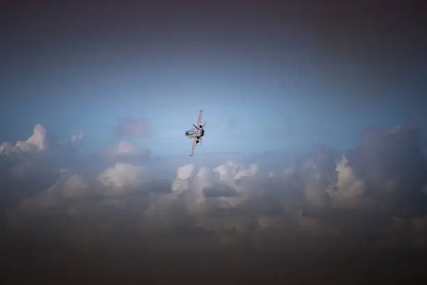 Fighter jet plane turning left in clouds