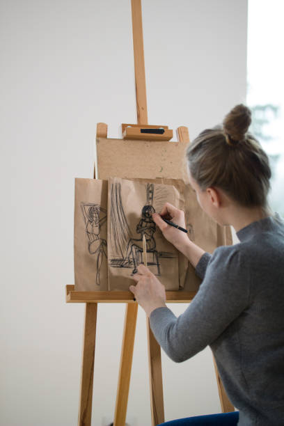 istock Rear view of female painter draws on the easel human figure 952121796