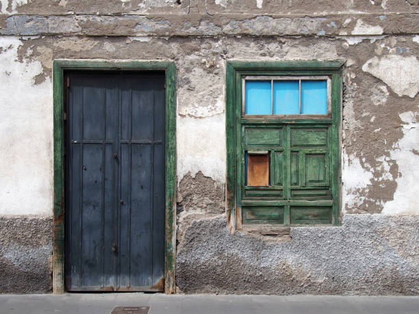 istock empty derelict small house with decaying bricks broken plaster and green windows with fading colors and black wooden door 952125090