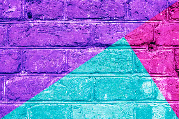 istock Textured brick wall with bright abstract pattern of colored triangles of green, violet and pink, abstract background. Concept of graphite walls, urban culture, aerosol pictures. 952127586