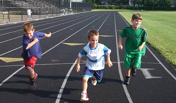 istock Three boys running on a track with the smallest in the lead 95214674
