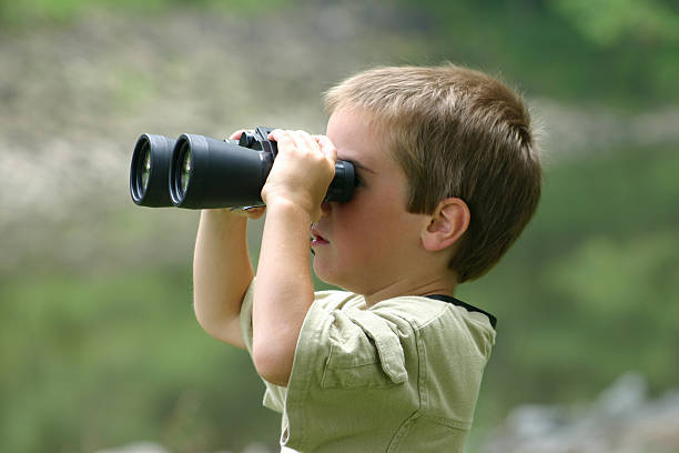 istock Young boy holding a pair of black binoculars looking through 95215170