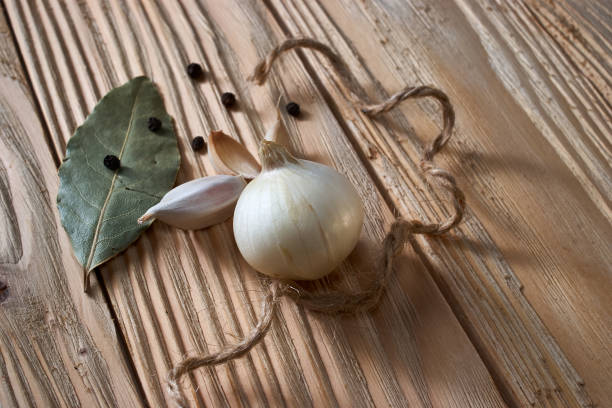 istock onion, garlic, black pepper and bay leaf on a wooden background 952188884