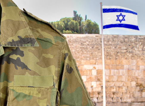 Military man posing in front of Israel flag and The Western Wall background in jerusalem