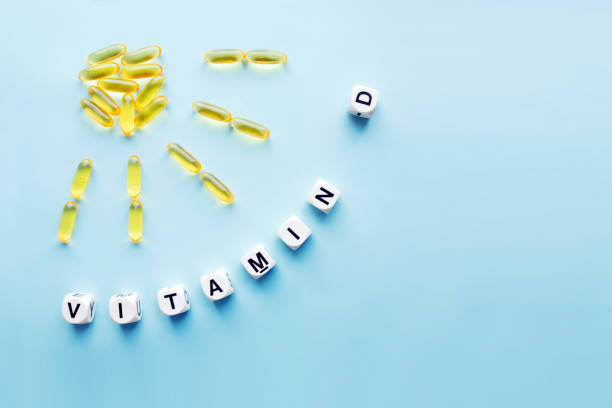 Yellow capsules in the form of the sun with rays and the word vitamin D from white cubes Yellow capsules in the form of the sun with rays and the word vitamin D from white cubes with letters on a blue background. VITAMIN D word for healthy and medical concept. Sunshine vitamin health benefits vitamin d stock pictures, royalty-free photos & images