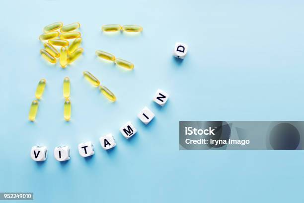 Yellow Capsules In The Form Of The Sun With Rays And The Word Vitamin D From White Cubes Stock Photo - Download Image Now