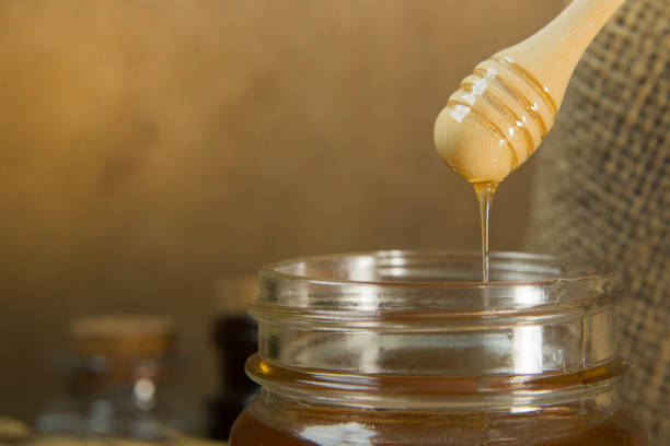 istock honey bee in glass bottle on wood  table. 952303844