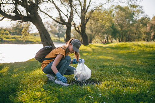 Young woman cleaning up garbage in the nature