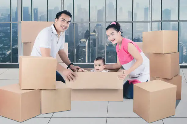 Young Asian family having fun unpacking boxes moving in to a new apartment