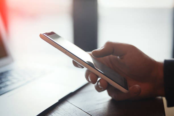 istock Young man holding mobile phone and working on laptop 952309856