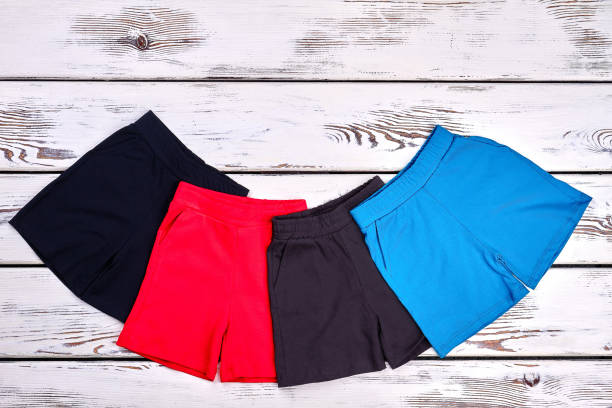 Set of kids colored cotton shorts. Collection of new brand shorts for childrens on white wooden background. Kids summer fashion style.
