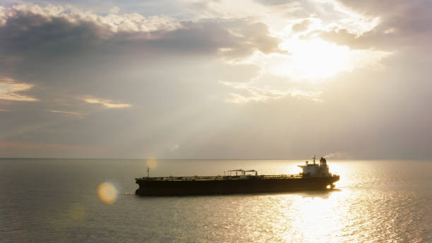 istock Cargo ship at sea as sun is peeking through dark clouds 952310074