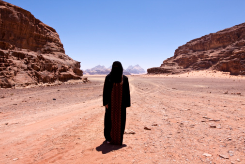 Nomadic woman dressed in Traditional burka standing alone in the the desert of jordan called 